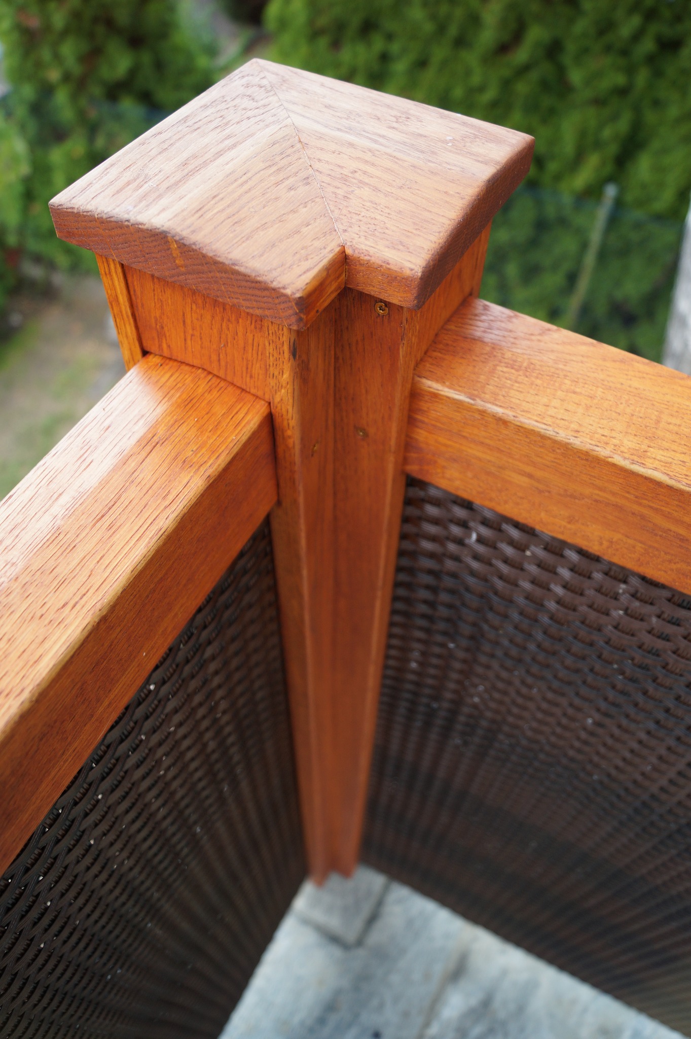 Fragment drewnianej balustrady z wypełnieniem z plecionki, widok z góry, ciepłe oświetlenie.