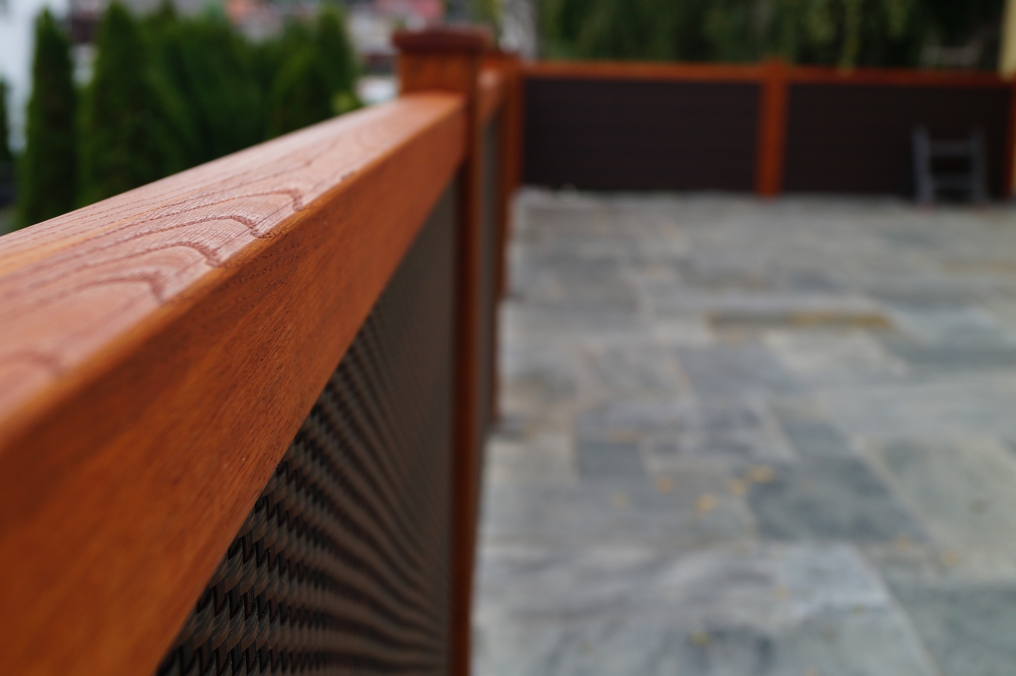 Drewniana balustrada z metalową siatką na tarasie, z widocznym fragmentem drabiny w tle.