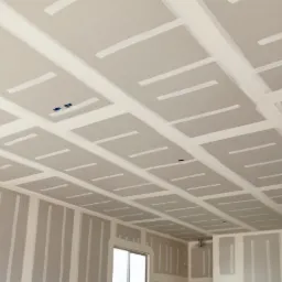 Sufit i ściany wykończone płytami gipsowo-kartonowymi, widoczne łączenia wzmocnione taśmą, przygotowane do dalszych prac wykończeniowych, z widocznymi otworami na instalacje.