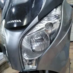 Przedni reflektor i owiewka motocykla Honda, widoczne ślady użytkowania na czarnej części owiewki.
