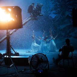 Tomasz Wilczkiewicz FOTOGRAF - Scena filmowa z baletnicami w białych sukniach podczas opadania sztucznego śniegu, widoczny operator kamery na wysięgniku, oświetlenie studyjne i wentylator na pierwszym planie.