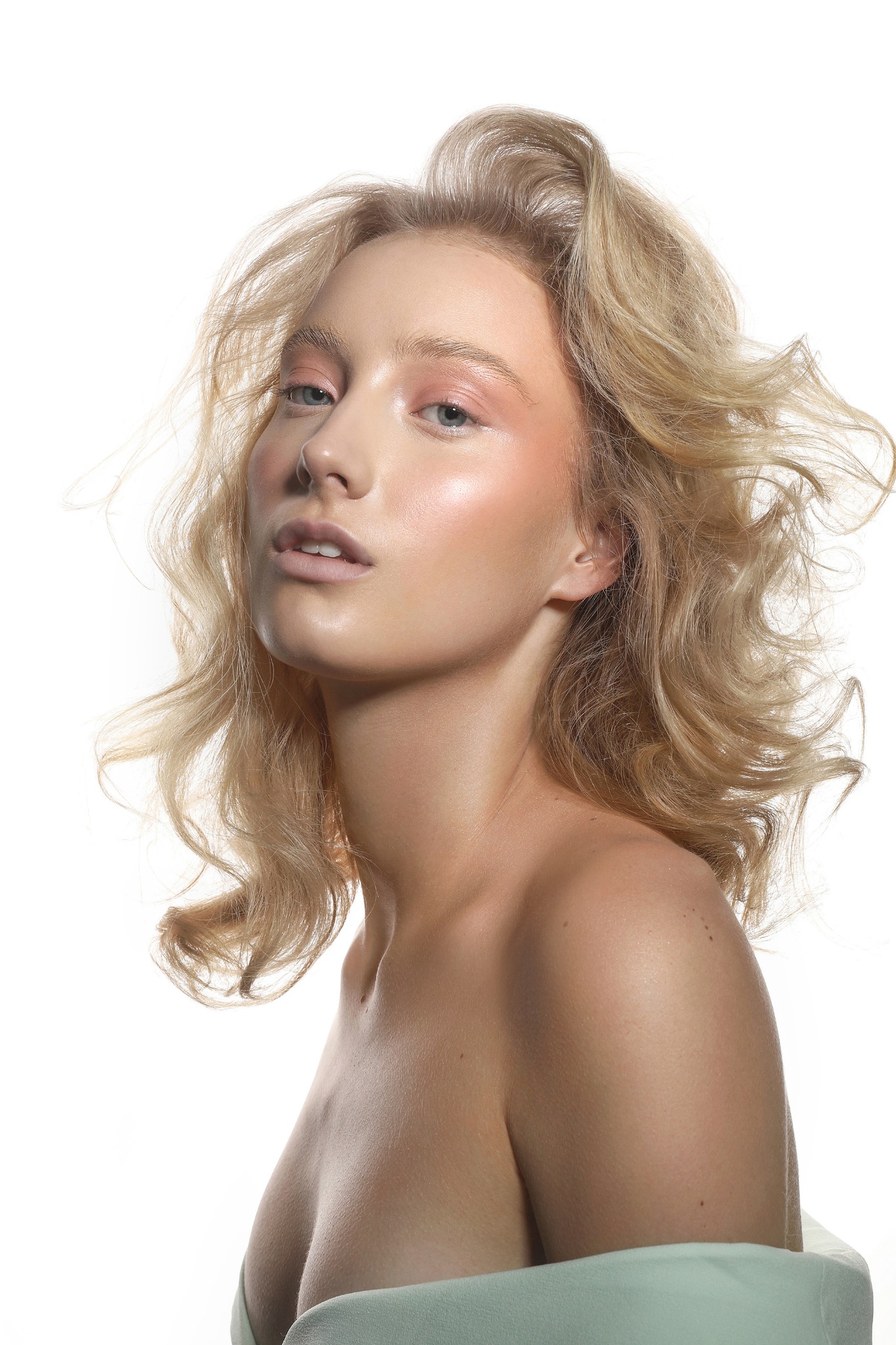 Portret kobiety z blond włosami i delikatnym makijażem w odcieniach różu, wykonany w studio w Poznaniu na białym tle.