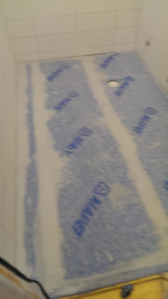 Przygotowanie podłoża pod prysznic z użyciem membrany hydroizolacyjnej z logo MAPEI, widoczny odpływ liniowy