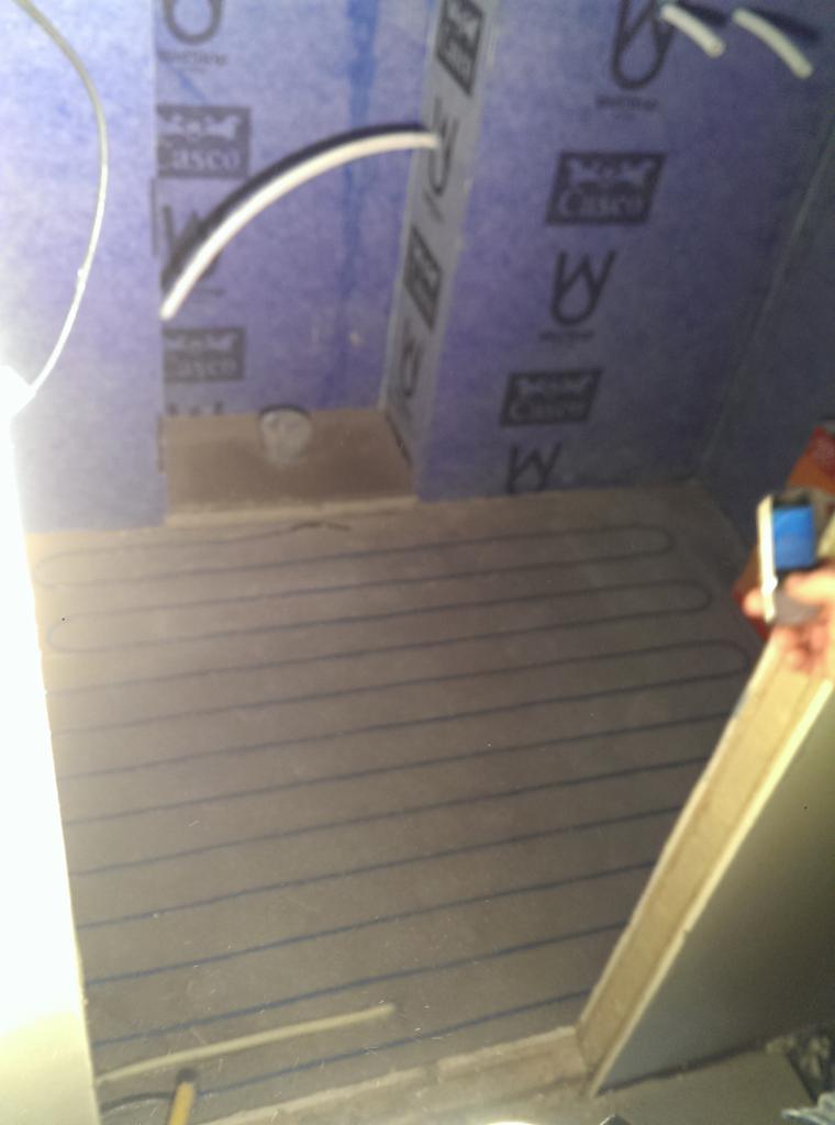 Poddasze w trakcie ocieplania, widoczne izolacja z nadrukiem, kable oraz fragment instalacji grzewczej podłogowej.