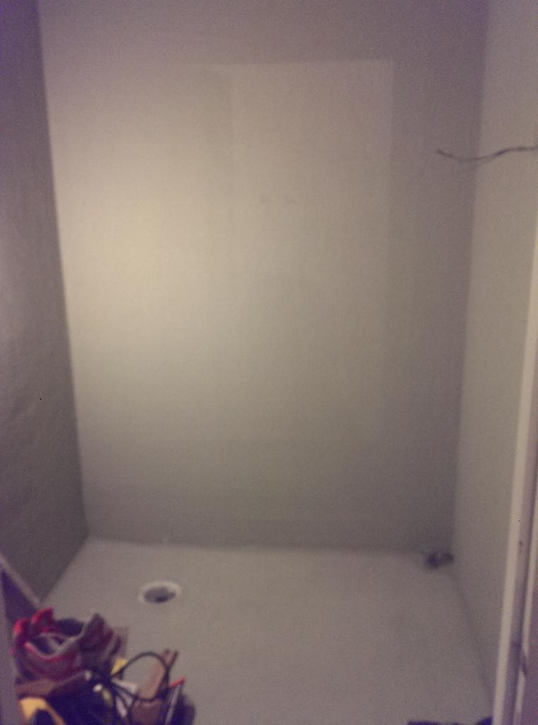 Puste, pomalowane na szaro pomieszczenie z otworem w podłodze, prawdopodobnie przygotowywane do remontu lub adaptacji poddasza.