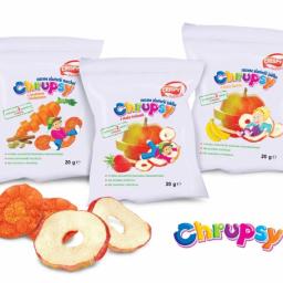 Red Tree Krzysztof Stasiak - Trzy białe opakowania suszonych plasterków owocowych i warzywnych marki Chrupsy: marchew z kardamonem, jabłko z truskawką i jabłko z bananem. Na pierwszym planie suszone plasterki marchewki i jabłka.