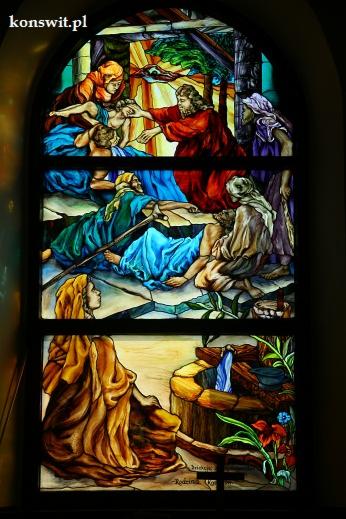 Witraż przedstawiający sceny biblijne w trzech panelach: uzdrowienie, scena z kijem i studnia z kobietą.