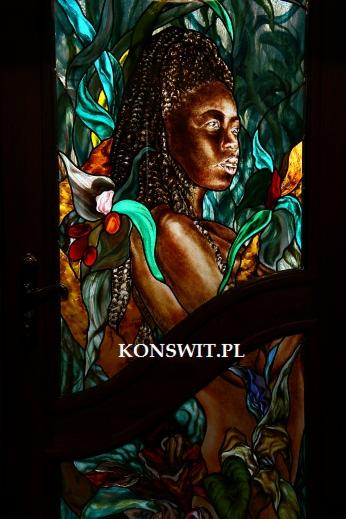 Barwny witraż przedstawiający kobietę o afrykańskich rysach w otoczeniu tropikalnej roślinności, z widocznym adresem strony internetowej w dolnej części.