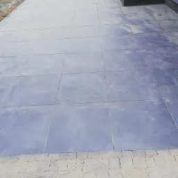 Nowoczesny taras z szarych płyt kamiennych, widok z góry, mokra powierzchnia po deszczu, zlewająca się kolorystyka z elewacją domu.