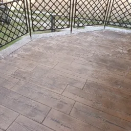 Wykończony taras z betonu stemplowanego imitującego drewniane deski, otoczony metalową balustradą z motywem kraty.