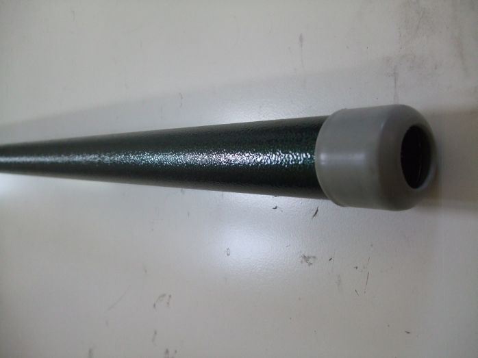 Metalowa rura pomalowana na ciemnozielony kolor z szarą plastikową zaślepką na końcu, leżąca poziomo na białym tle.