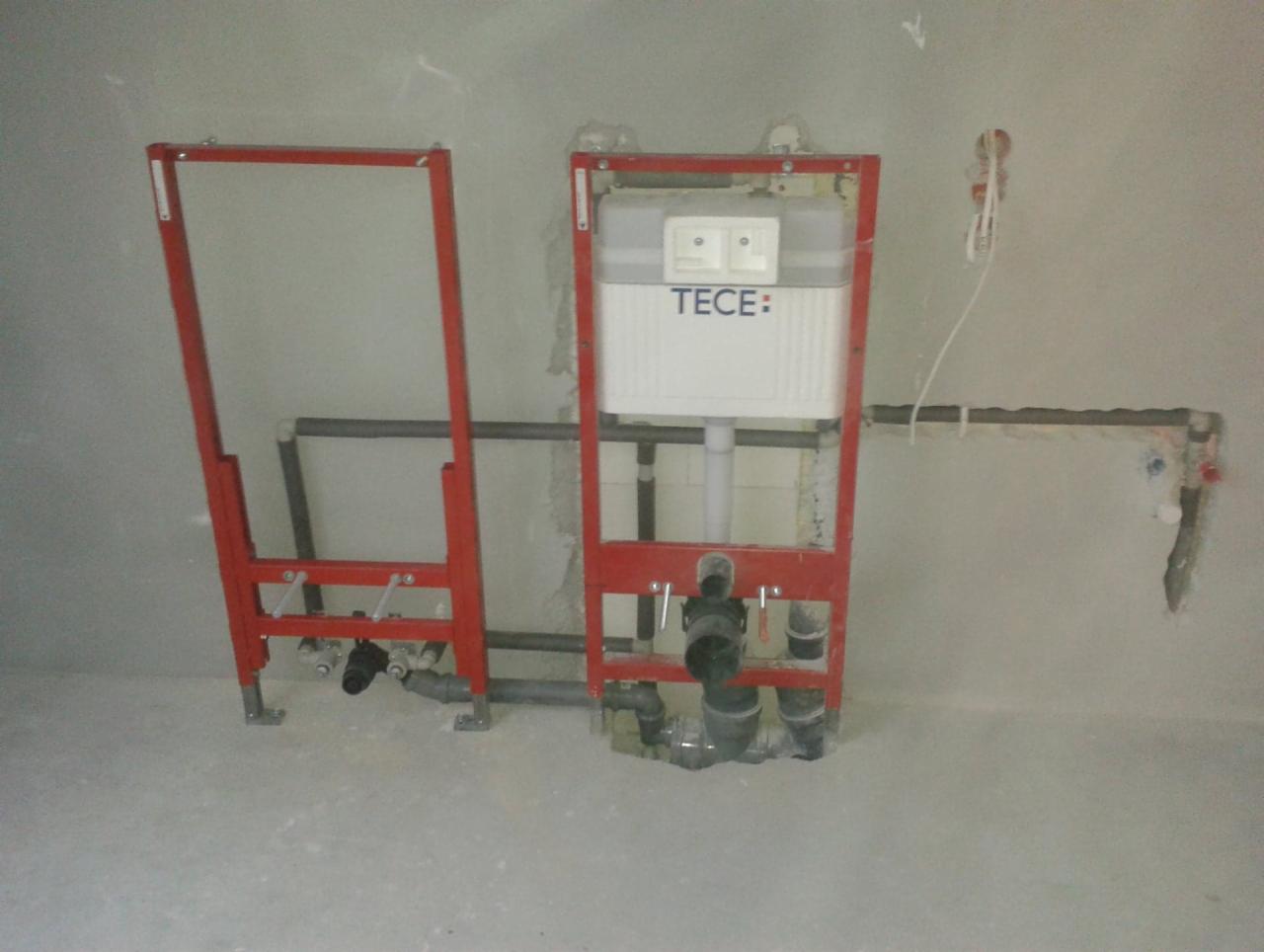 Stelaż podtynkowy TECE do WC w trakcie montażu, widoczne rury instalacyjne i przewody elektryczne w surowym stanie