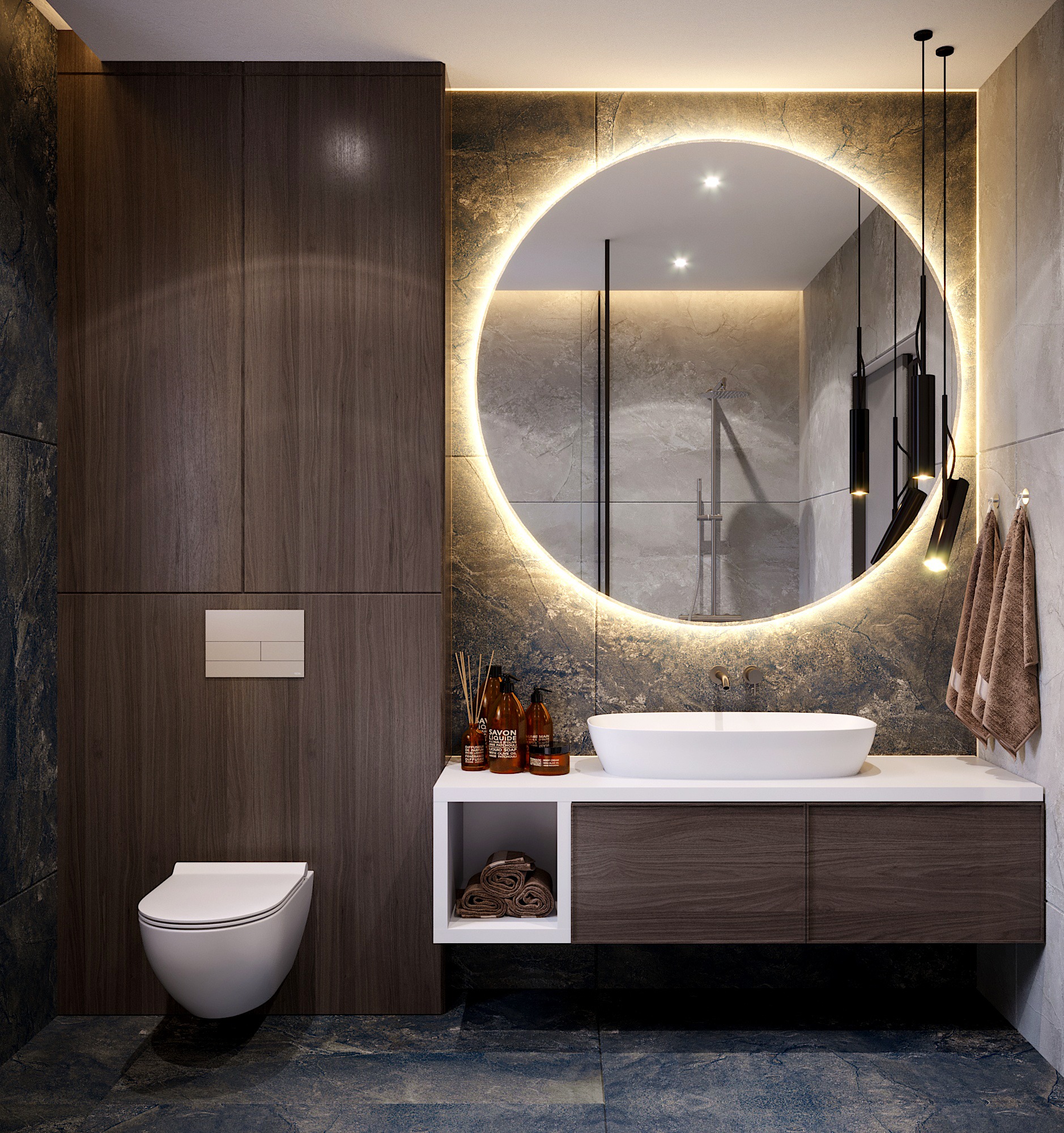 Nowoczesna łazienka z okrągłym lustrem podświetlanym LED, wiszącą toaletą i umywalką nablatową, wykończona płytkami imitującymi kamień i drewnem w ciepłych odcieniach.