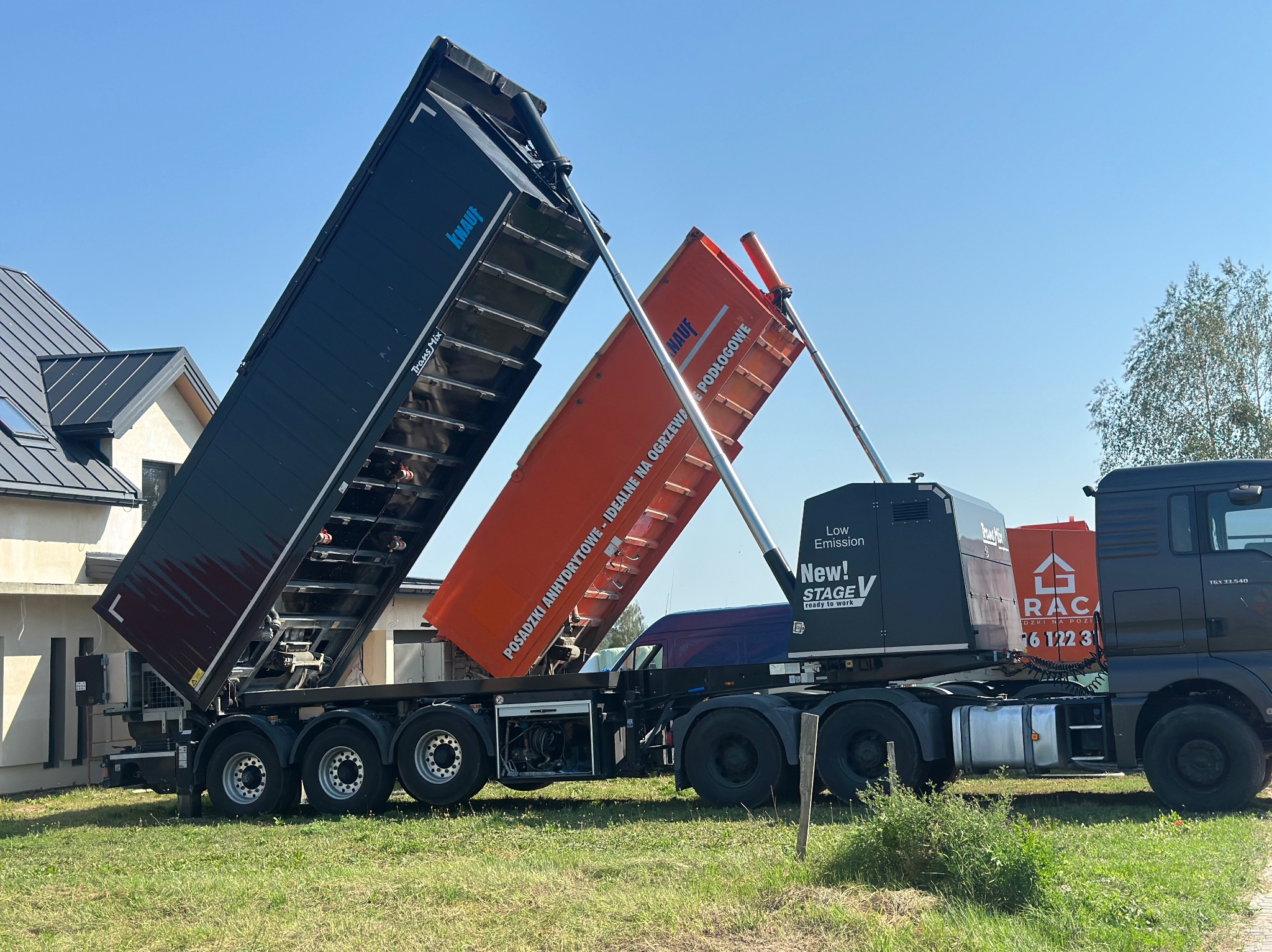 Ciężarówka z dwiema otwartymi naczepami, jedna czarna z logo Knauf, druga pomarańczowa z napisem 'Posadzki anhydrytowe - idealne na ogrzewanie podłogowe'.