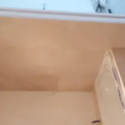 Beżowy blat w łazience, zamontowany pod oknem, widoczne niedoskonałości w wykończeniu ściany.