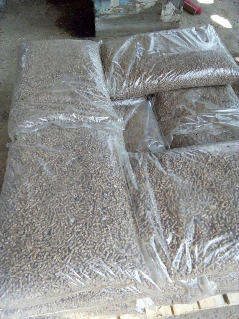 Worki z granulatem opałowym na palecie, widoczne drobne nierówności w strukturze granulatu przez przezroczyste worki.