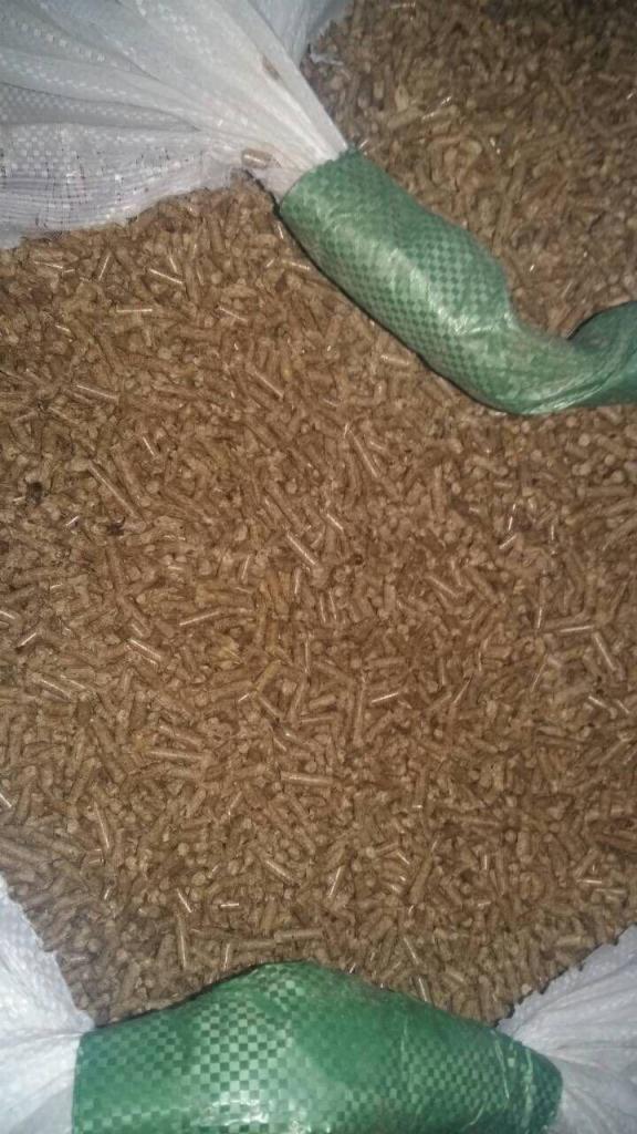 Jasnobrązowy pellet drzewny w worku z zielonym wzmocnieniem, widoczne pojedyncze granulki