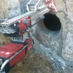 Wiertnica diamentowa Hilti wiercąca otwór w betonowym fundamencie; widoczne ślady wiercenia i pył.