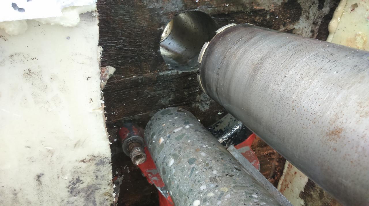 Wiertło koronowe w trakcie wiercenia otworu w konstrukcji; widoczne rdzenie betonowe.