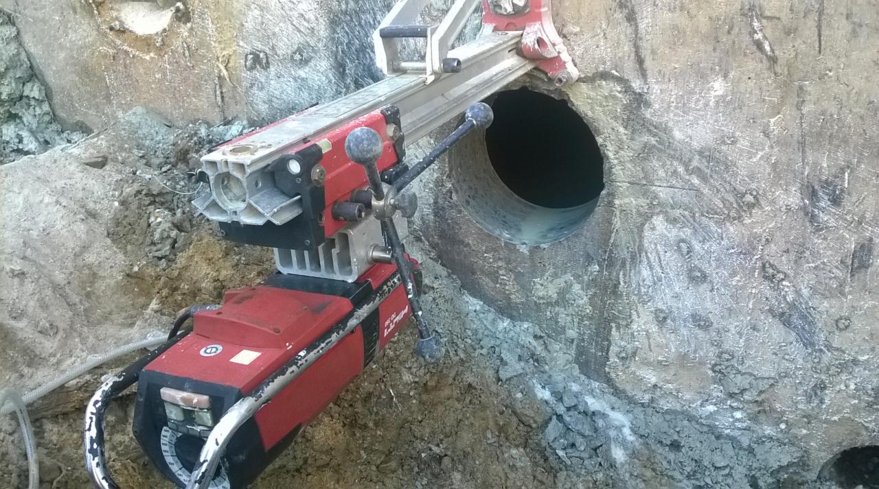 Wiertnica diamentowa Hilti wiercąca otwór w betonowym fundamencie; widoczne ślady wiercenia i pył.