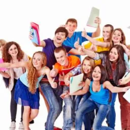 Grupa roześmianych, młodych ludzi z notatnikami i kciukami w górę na białym tle, sugerująca pozytywne doświadczenia edukacyjne.