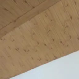 Pionowe panele drewniane na poddaszu, z widocznym łączeniem i fragmentem białej ściany poniżej, sfotografowane pod kątem.