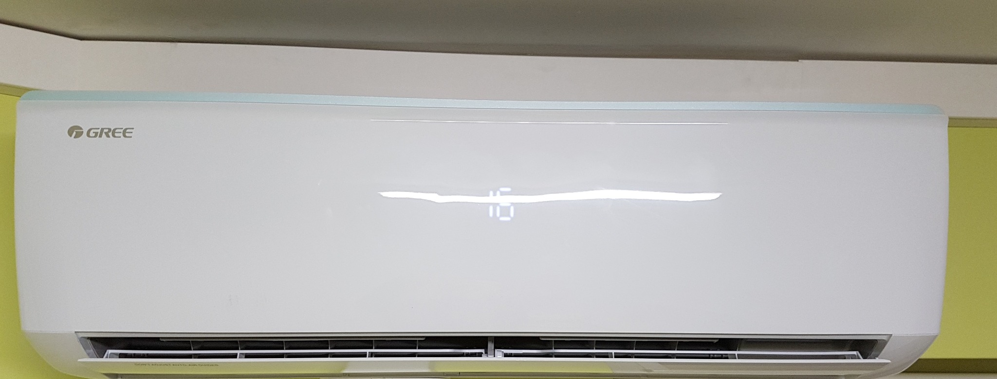 Biała klimatyzacja marki Gree zamontowana na ścianie, wyświetlająca temperaturę 16 stopni Celsjusza.