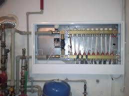 Rozdzielacz ogrzewania podłogowego z podłączonymi rurami w szafce, widoczne elementy instalacji hydraulicznej w Jankowicach.