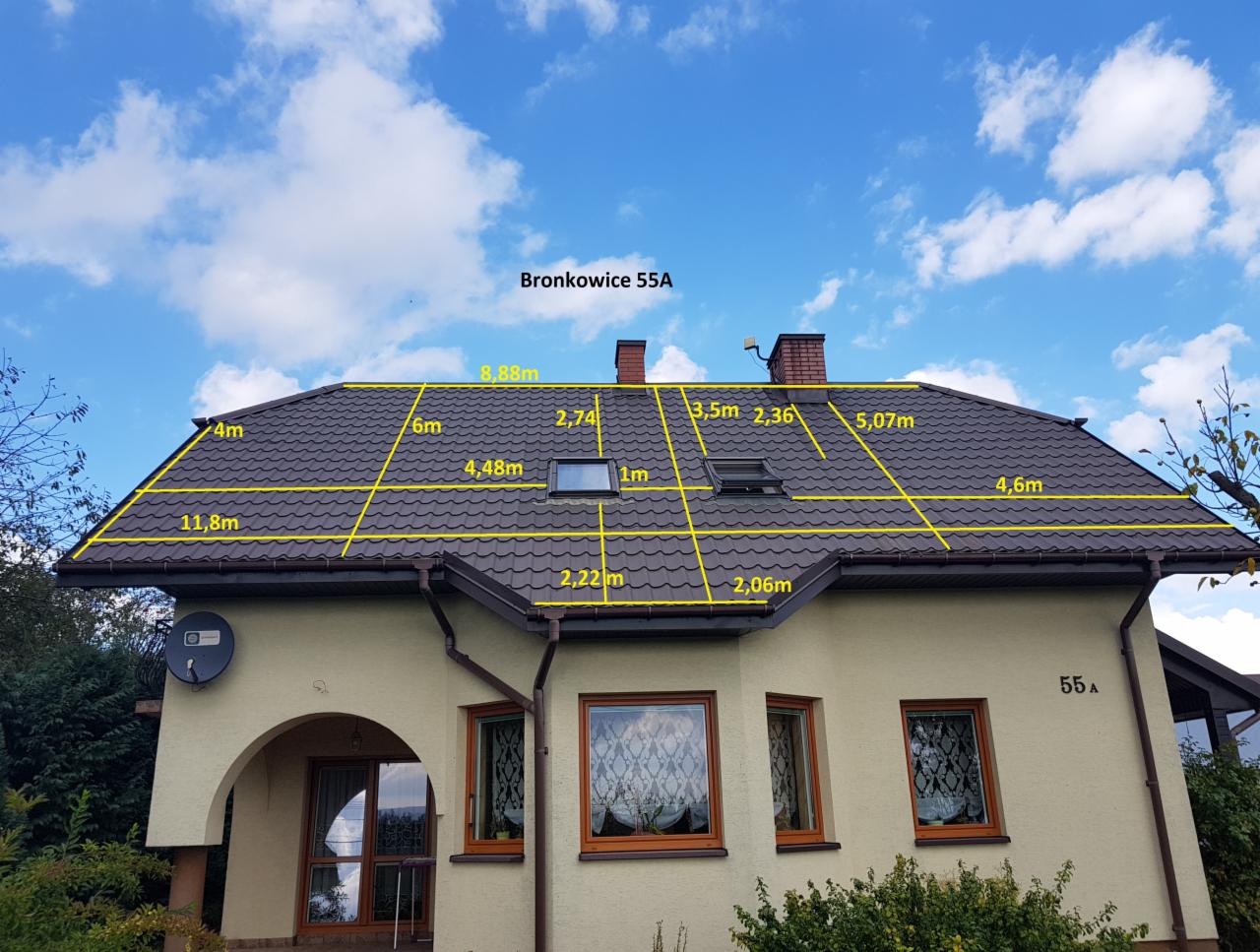 Dom jednorodzinny z brązowym dachem, na którym naniesiono żółte linie z wymiarami poszczególnych fragmentów połaci dachowej na tle błękitnego nieba z chmurami.