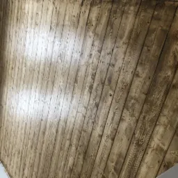 Świeżo polakierowana drewniana podłoga z widocznymi słojami, ułożona z desek wzdłuż ściany z grzejnikiem.