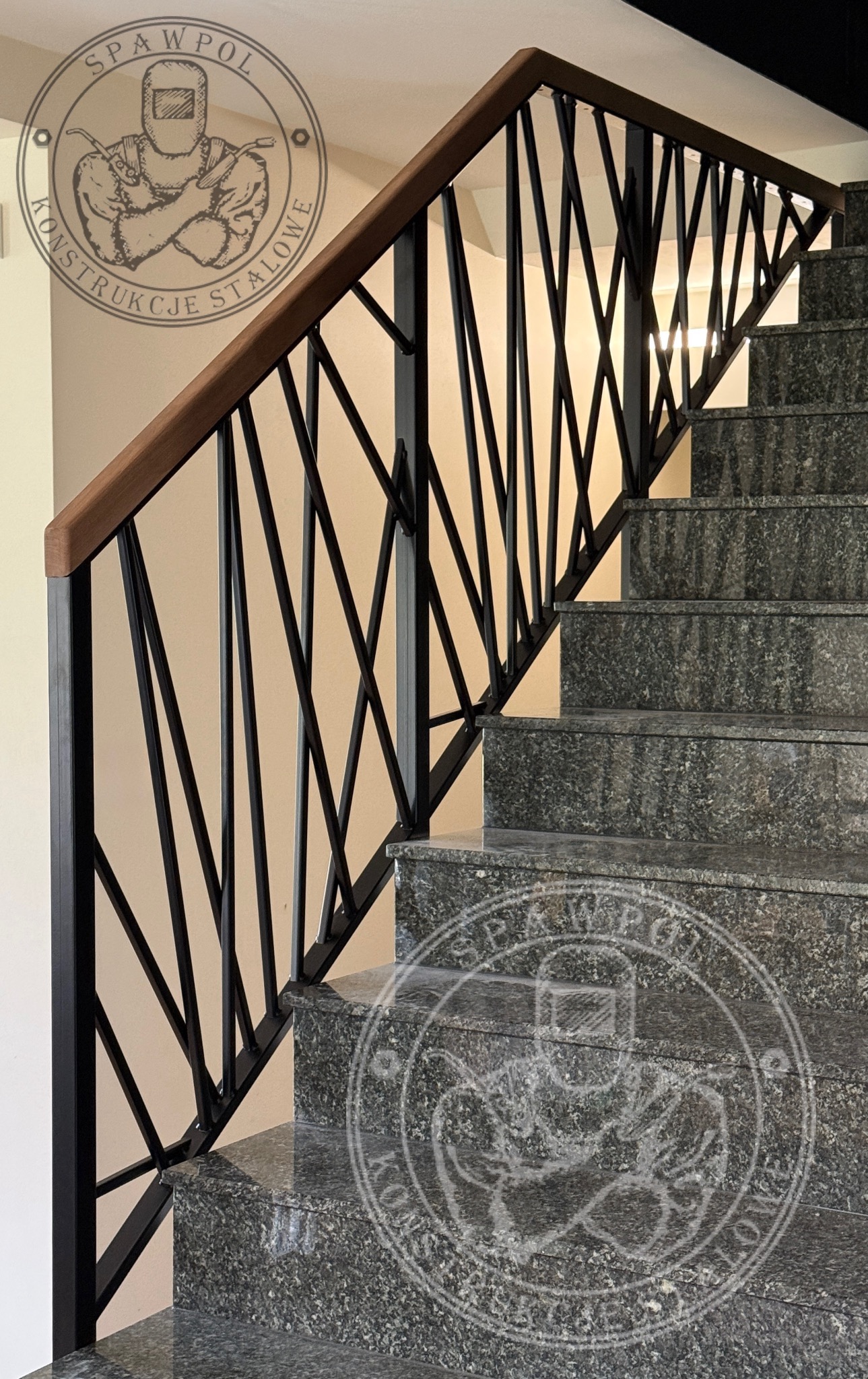 Nowoczesna balustrada schodowa z czarnych, metalowych prętów o nieregularnym układzie i drewnianym pochwytem, zamontowana na granitowych schodach.