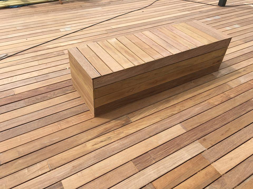 Świeżo ułożony drewniany taras z dopasowaną, geometryczną ławką z desek, wykończony w naturalnym odcieniu drewna.
