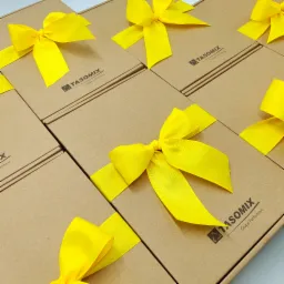 Równy rząd kartonowych pudełek z logo firmy i jaskrawożółtymi wstążkami, gotowych do wręczenia.