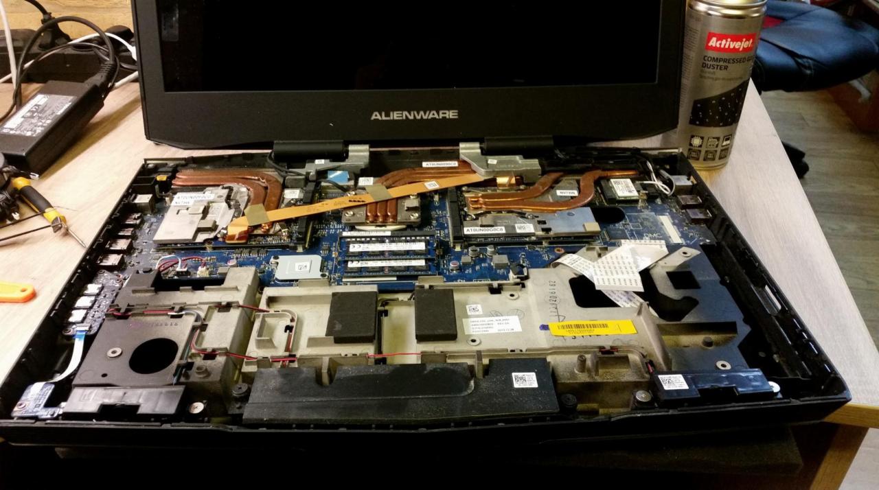 Otwarty laptop Alienware z widoczną płytą główną, układem chłodzenia i innymi komponentami wewnętrznymi, obok leży sprężone powietrze w puszce i narzędzia.