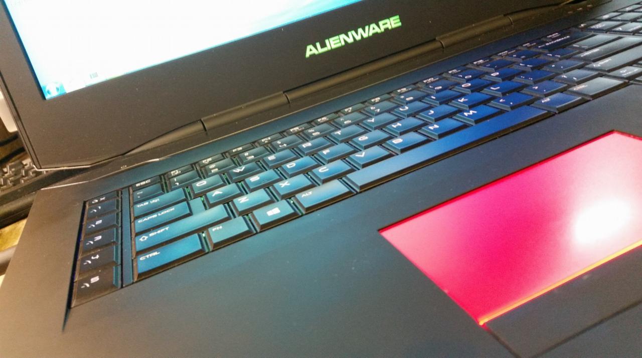 Czarny laptop Alienware z podświetlaną klawiaturą i touchpadem w kolorze czerwonym, widoczne logo Alienware.