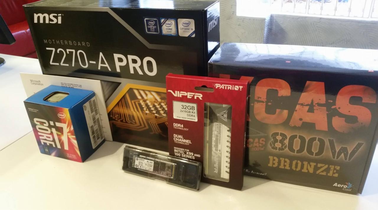 Komponenty komputerowe w pudełkach na białym stole: płyta główna MSI Z270-A PRO, procesor Intel Core i7, pamięć RAM Patriot Viper 32GB DDR4, dysk SSD i zasilacz AeroCool CAS 800W Bronze.