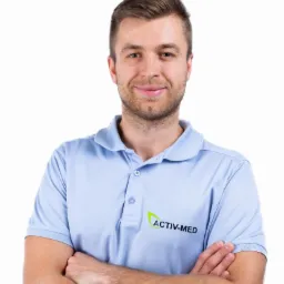 Portret uśmiechniętego mężczyzny w błękitnej koszulce polo z logo 'Activ-Med' na białym tle, ręce skrzyżowane.