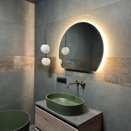 Mieszkanie w Twoim stylu - Nowoczesna łazienka z zieloną umywalką nablatową, podświetlanym lustrem i szarą glazurą z dekoracyjnym pasem. Minimalistyczne lampy wiszące.