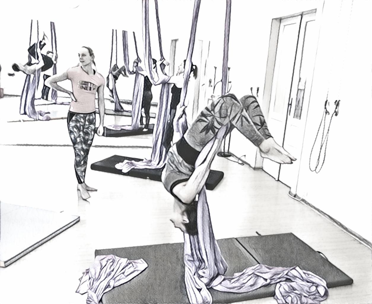 Kobieta w pozycji odwróconej, ćwicząca aerial silks w studio, instruktorka obserwuje