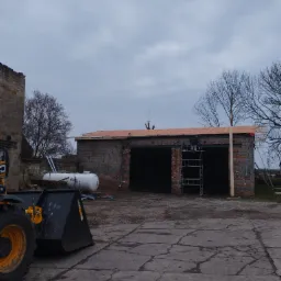 Montaż pokrycia dachowego na budynku gospodarczym w Stargardzie, widoczny pracownik na rusztowaniu oraz zbiornik na gaz.