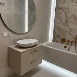 Lepsze Meble - Jasna łazienka z szafką pod umywalkę na wymiar, okrągłe lustro z folią ochronną i wanną z podświetleniem LED. Złota armatura.