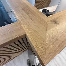 Rychert Holzdesign - Detal drewnianej konstrukcji z bliska, ukazujący precyzyjne połączenie elementów i naturalny rysunek drewna. Widoczne elementy biurka i dekoracji ściennych.