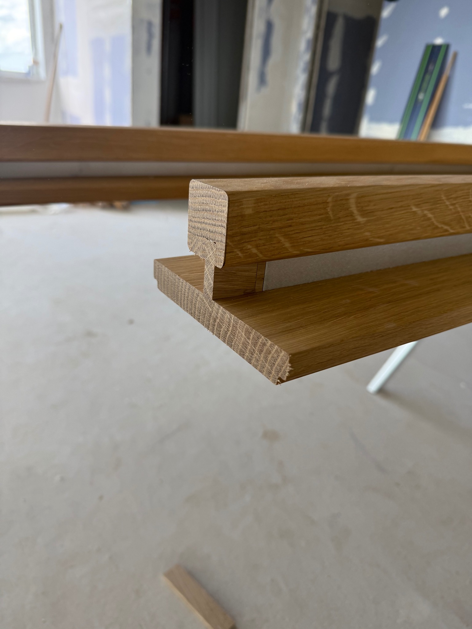 Detal drewnianego elementu konstrukcyjnego z widocznym usłojeniem, prawdopodobnie fragmentu schodów lub balustrady w surowym wnętrzu.