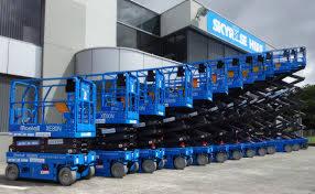 Rząd niebieskich podnośników nożycowych ustawionych obok budynku z logo 'SKYRISE HIRE'.