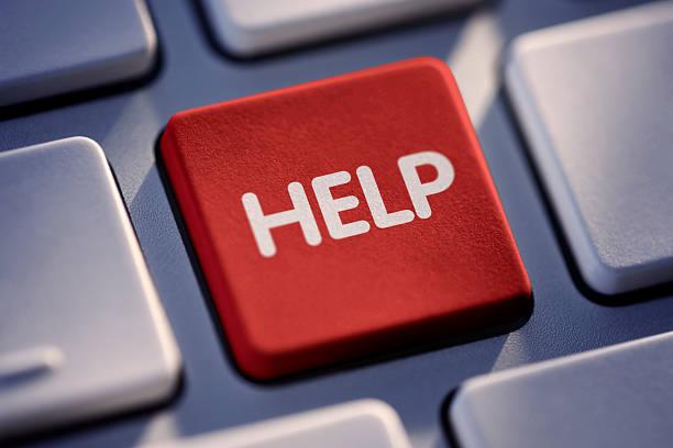Czerwony klawisz z napisem 'HELP' na klawiaturze komputera, otoczony szarymi klawiszami. Klawisz pomocy jest lekko wciśnięty, co sugeruje jego użycie.