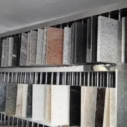 Ekspozycja próbek różnych rodzajów kamienia na metalowym stojaku w sklepie, widoczne różne kolory i wzory.