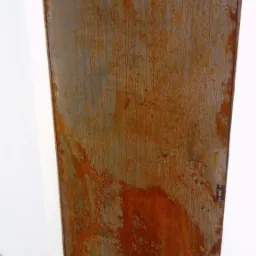 Metalowa brama z efektem rdzy, umieszczona pomiędzy dwoma białymi filarami, z widocznym zamkiem i fragmentem chodnika z kostki brukowej.