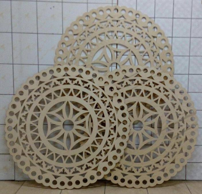 Ozdobne, ażurowe podkładki z drewna wykonane przez stolarza w Warszawie, ułożone na kafelkach.