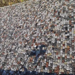 Szeroki kadr na ułożoną nawierzchnię z drobnej kostki o zróżnicowanej kolorystyce, od szarości po rdzawoczerwone odcienie, tworzącej mozaikowy wzór.