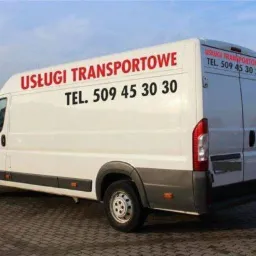 Biały samochód dostawczy z czerwonym napisem 'USŁUGI TRANSPORTOWE TEL. 509 45 30 30' z boku i z tyłu, zaparkowany na brukowanej powierzchni.